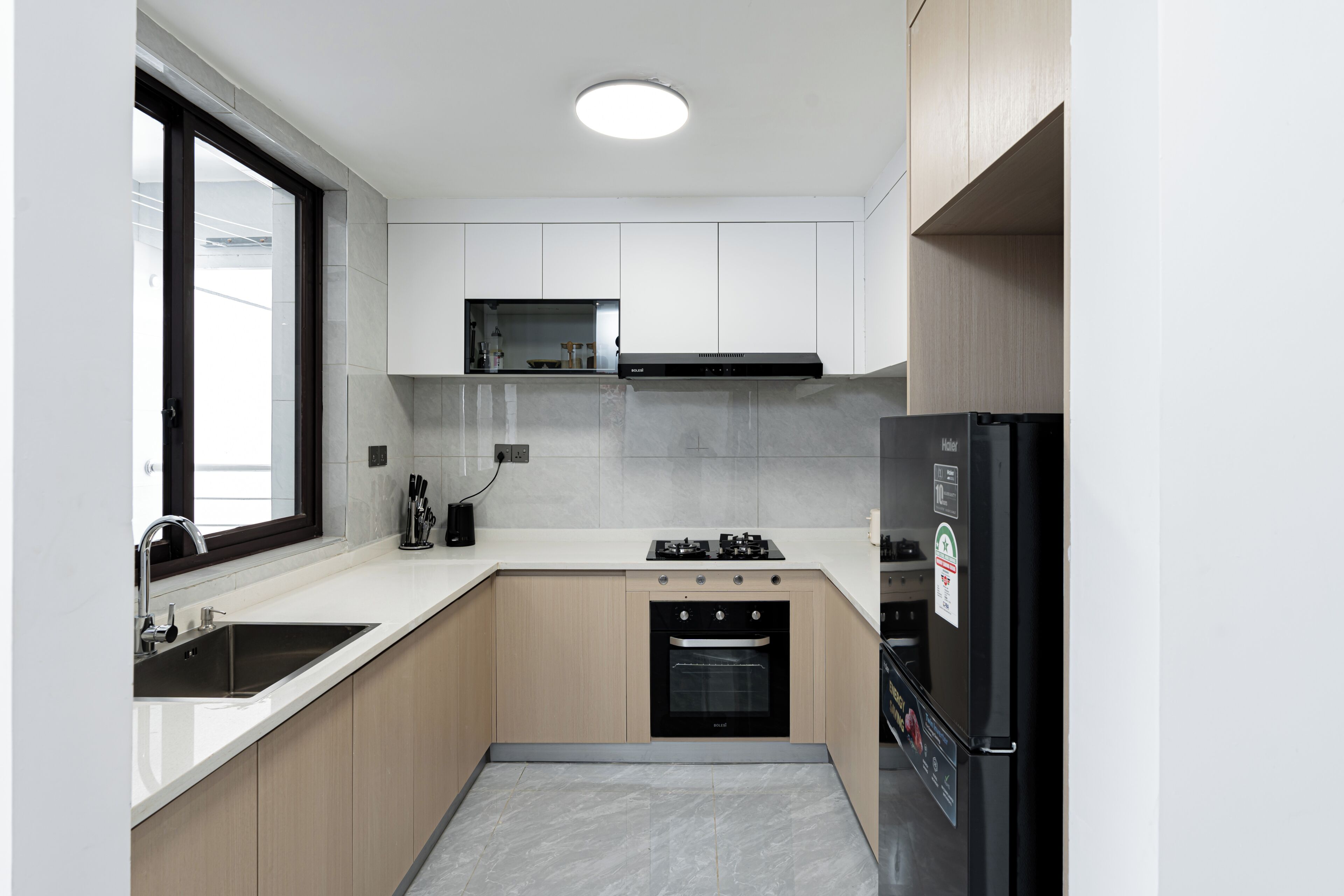 Una cocina moderna con horno empotrado, estufa a gas y refrigerador.