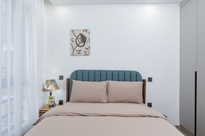 A neatly made bed with a headboard, a bedside lamp, and a wall-mounted artwork.