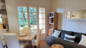 A modern living room with a dining area, a grey sofa, and a wooden table. - Air-conditioned Mazet Romarin - private terrace- shared swimming pool- Vallée des Baux (Paradou)