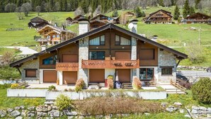 A large wooden chalet with a stone facade, multiple balconies, and a view of a green valley.