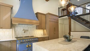 Una cocina con gabinetes de madera, una campana extractora azul y una encimera de mármol.