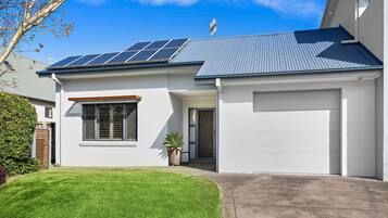 A modern house with solar panels, a garage, and a well-maintained lawn.