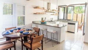 A modern kitchen with a central island, bar stools, and a dining table set for four.