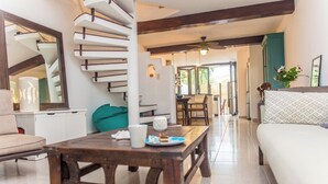 A modern living room with a spiral staircase, a dining area, and a sofa.