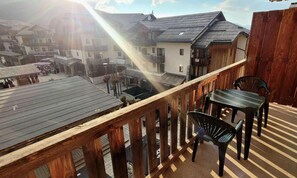 En balkon med trægelænder, et bord og to stole.