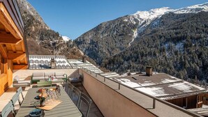 En modern utomhusterrass med en matplats, sittplatser och utsikt över snötäckta berg.