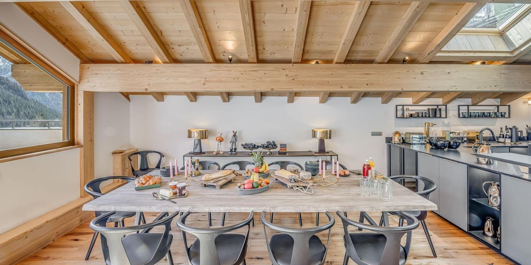 Een eetruimte met een houten tafel, stoelen en een keuken op de achtergrond.