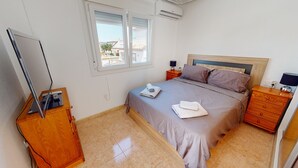 Una camera da letto con un letto, un comodino in legno, una scrivania con un computer e una finestra con persiane.