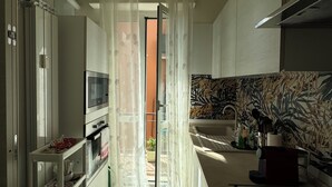 A modern kitchen with a central island, a dining area with a patterned rug, and a view into the adjacent living space. - Harmony in the green Veronese (Verona)