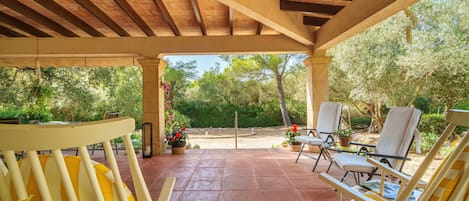 Un patio couvert avec des sièges et une vue sur le jardin.