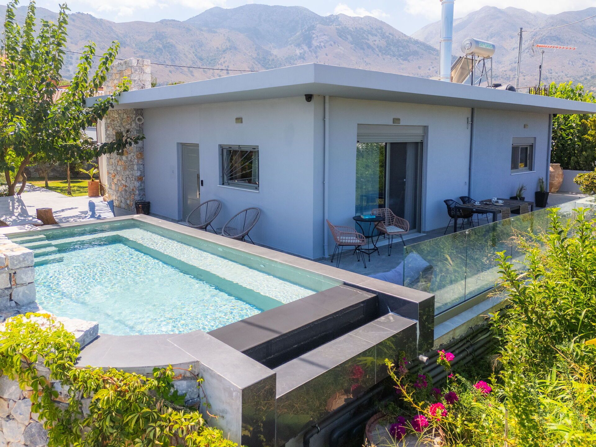Une maison moderne dotée d’une piscine, d’un espace salon extérieur et offrant une vue sur les montagnes.