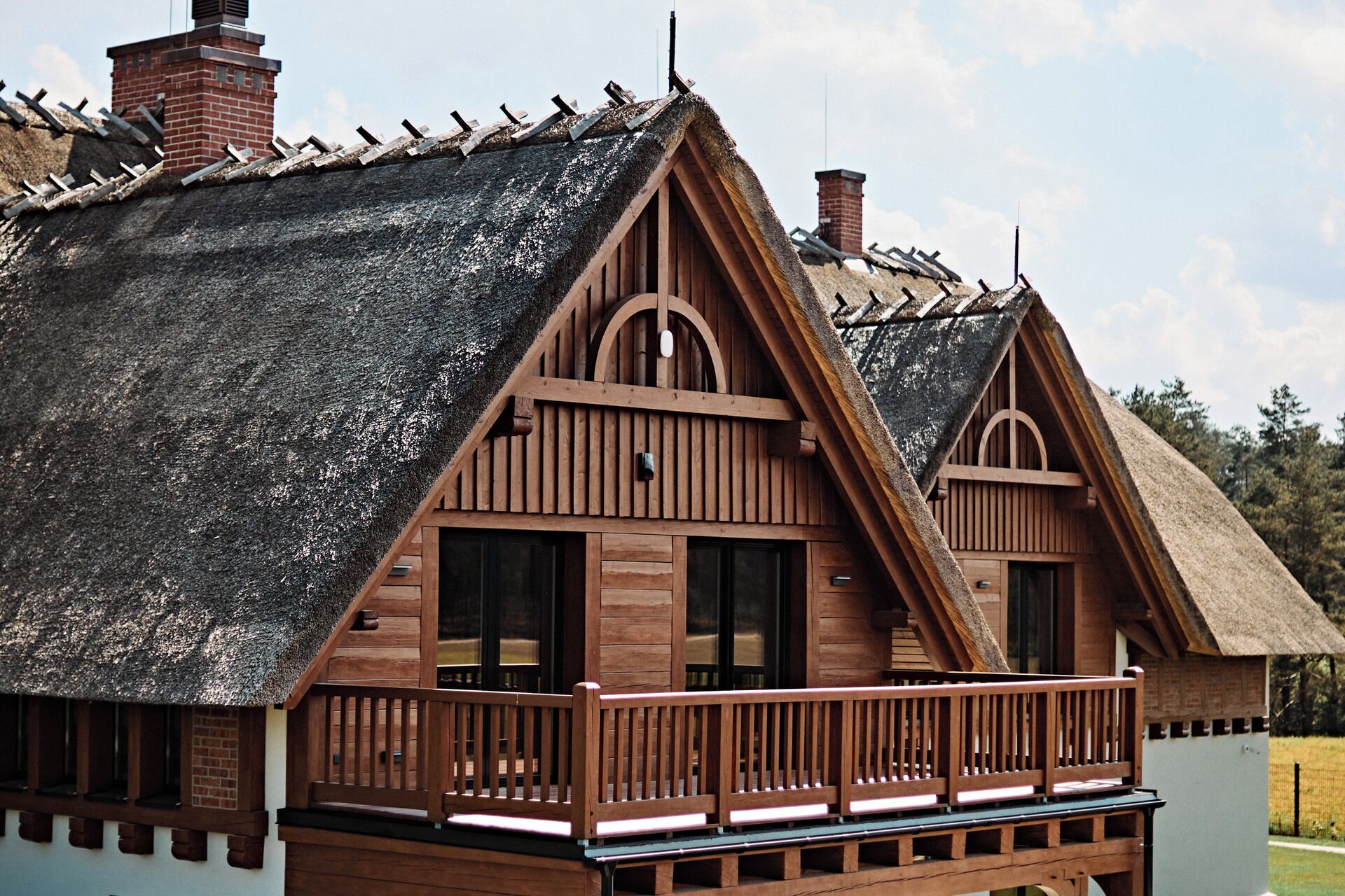 A wooden house with a steeply pitched roof and a balcony.