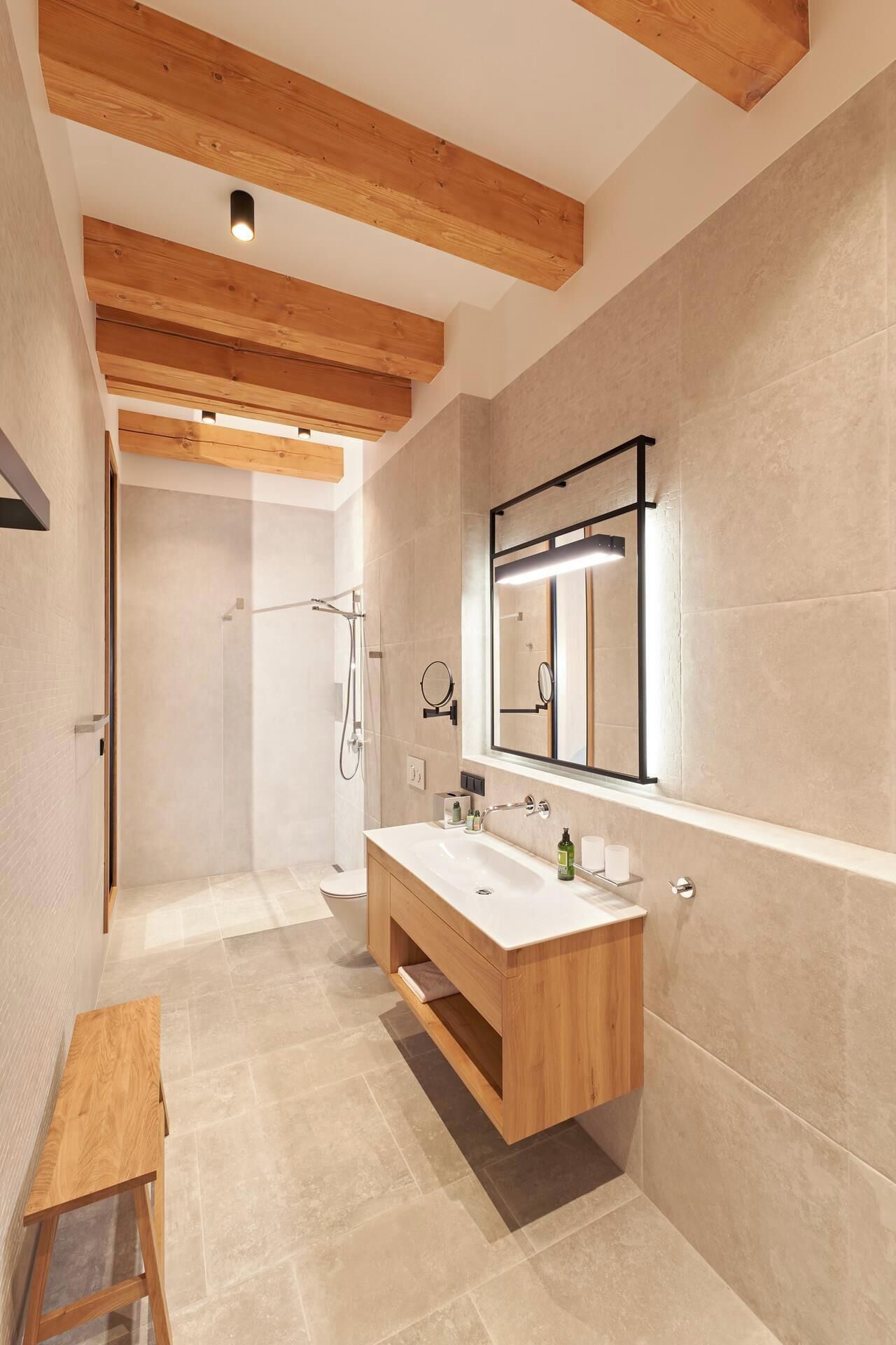 Un bagno moderno con un mobile bagno in legno, uno specchio grande e una doccia a ingresso libero.