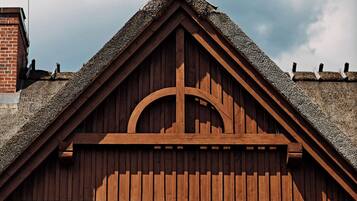 A wooden chalet with a steeply pitched roof, a balcony with wooden railings, and two large windows.
