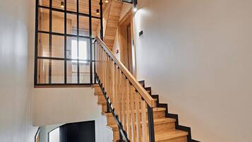 A wooden staircase with black railings and a hanging light fixture.