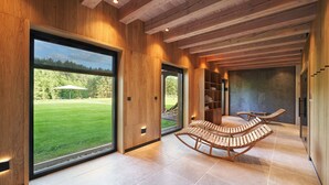 A modern interior with wooden beams, large windows, and a seating area with wooden loungers. - Siedlisko Milachowo luxury wellness (Brusy)