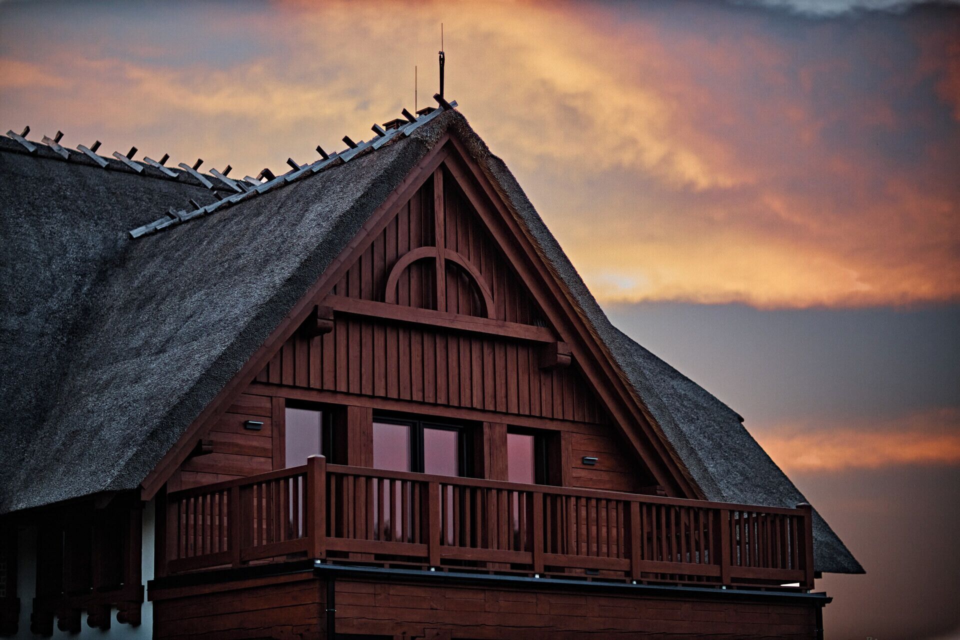 A wooden building with a steeply pitched roof and a balcony.