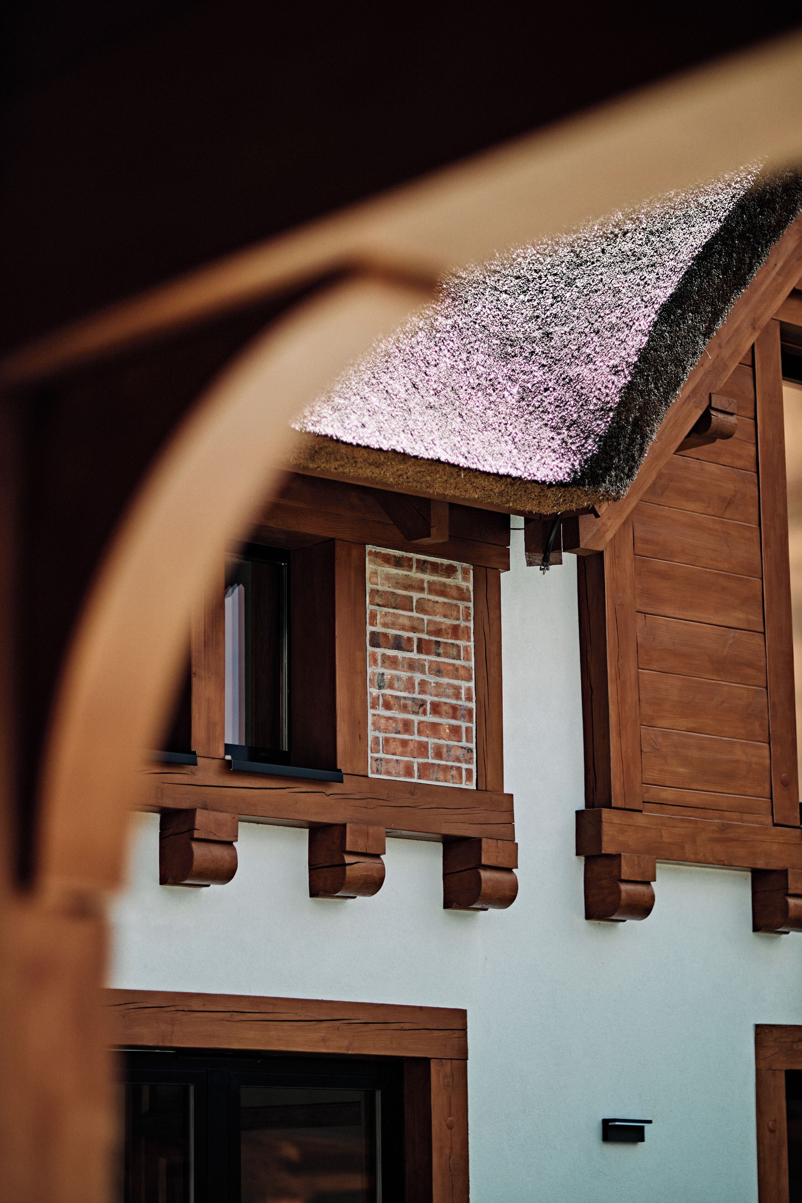 A building with a sloped roof, wooden beams, and a brick wall.