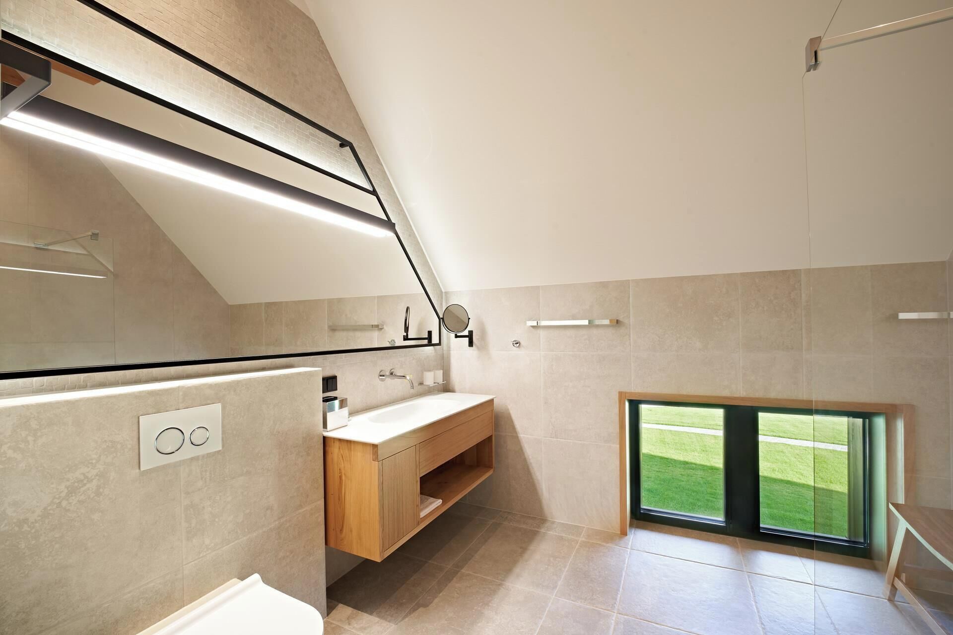 Une salle de bain moderne dotée d’un puits de lumière, d’un meuble-lavabo en bois et d’un grand miroir.