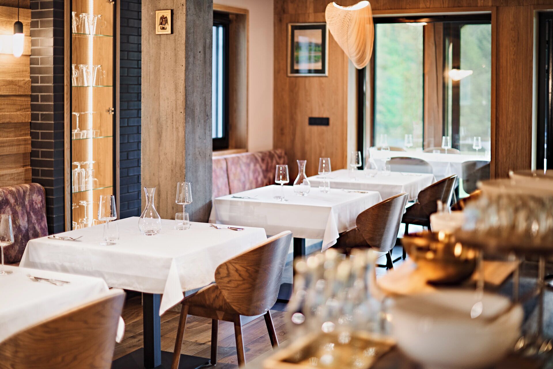 A restaurant with multiple tables and booths, each with white tablecloths and glassware.
