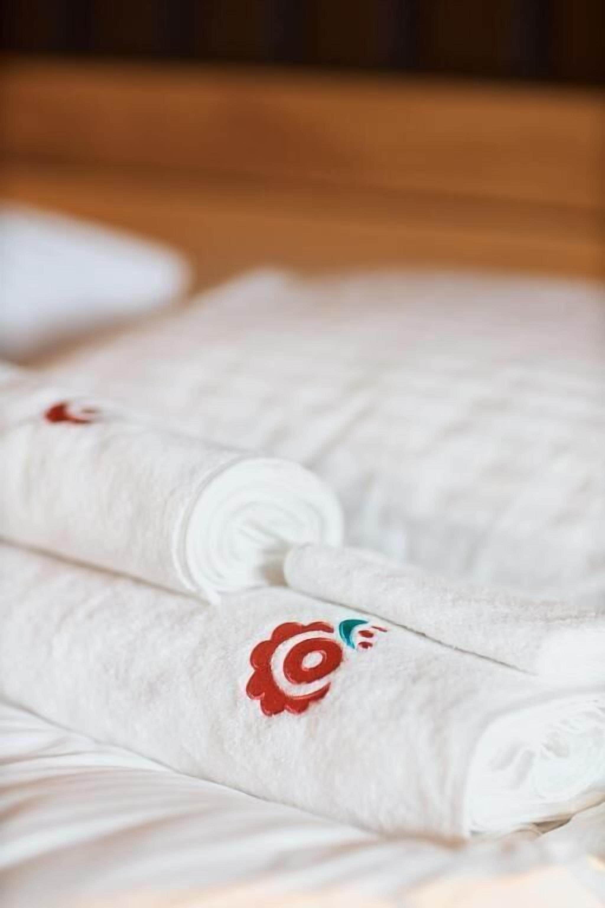 Una toalla blanca doblada con un diseño floral rojo sobre una superficie de madera.