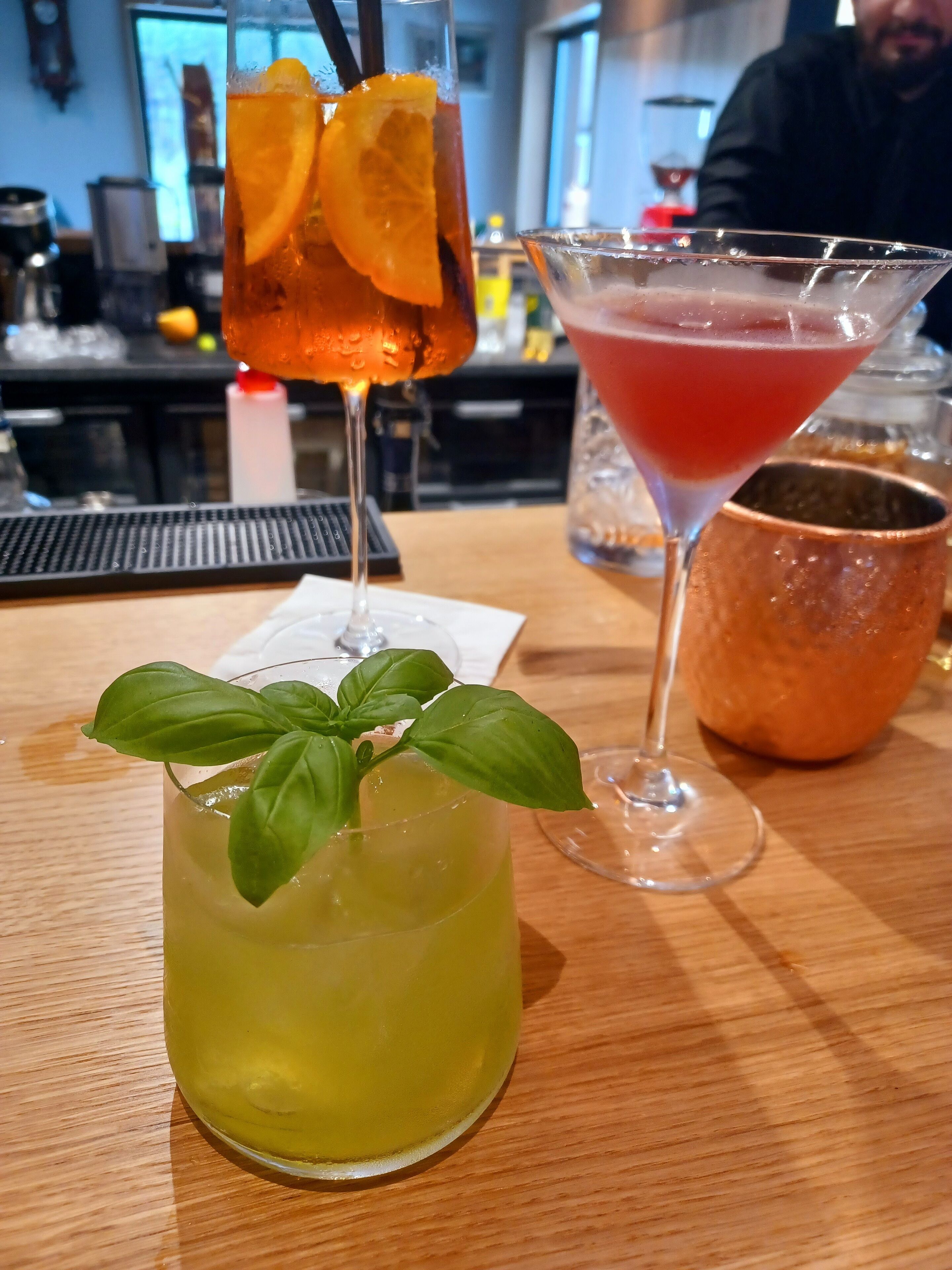 A bar area with a variety of drinks, including a martini and a cocktail with an orange slice garnish.
