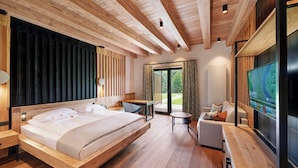 A modern hotel room with a wooden ceiling, a large bed, a desk, a chair, and a TV. - Siedlisko Milachowo luxury wellness (Brusy)