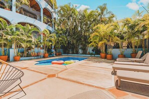 A pool area with lounge chairs, potted plants, and a clear blue sky. - Casa Del Morro - Studio Oasis with heated pool (Sayulita)