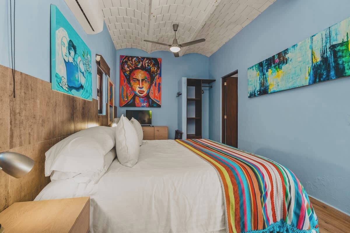 A bedroom with a bed, a ceiling fan, and artwork on the walls.