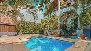 Una piscina con sillones de descanso y plantas en macetas.