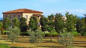 Edifici de pedra amb teulada acollidora, envoltat d'un jardí ben cuidat i arbres diversos.