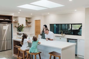 A modern kitchen with a central island, a refrigerator, and a dishwasher.