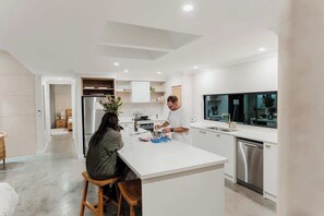 A modern kitchen with white cabinetry, stainless steel appliances, and a central island.