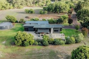 A modern house with a large patio, surrounded by lush greenery and a well-maintained lawn.