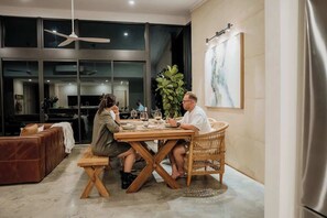 A dining area with a wooden table, wicker chairs, and a large window.