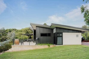 A modern house with a flat roof, large windows, and a covered outdoor area.