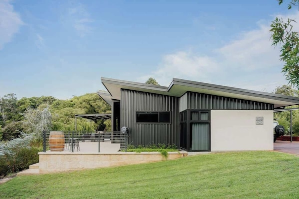 A modern house with a flat roof, large windows, and a covered outdoor area.