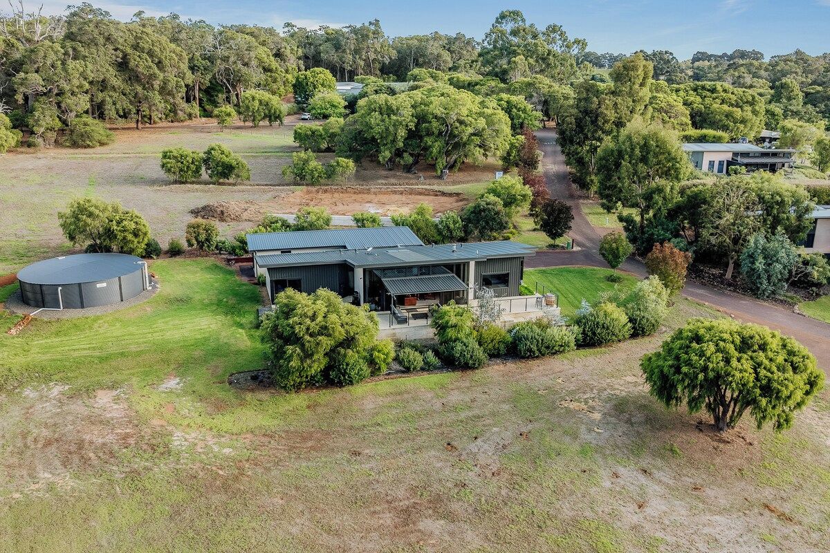 A modern house with a flat roof, surrounded by a well-maintained lawn and mature trees.