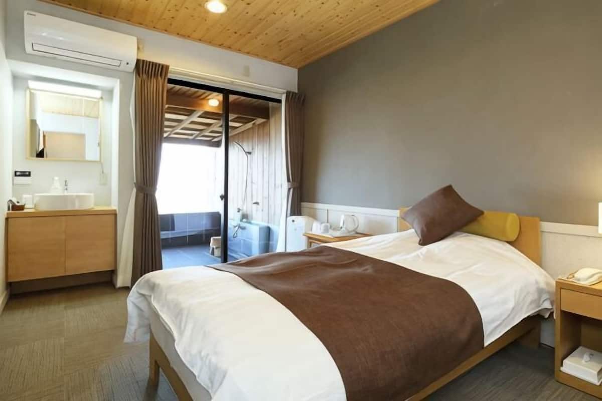 A hotel room with a bed, bedside table, and a bathroom with a sink and mirror.