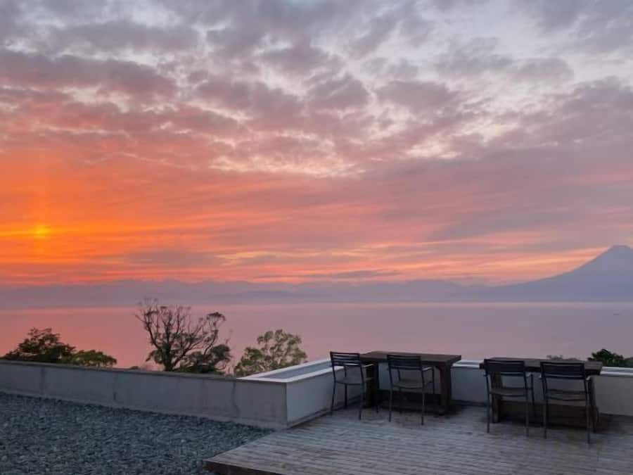 A sunset view from a terrace with a table and chairs.