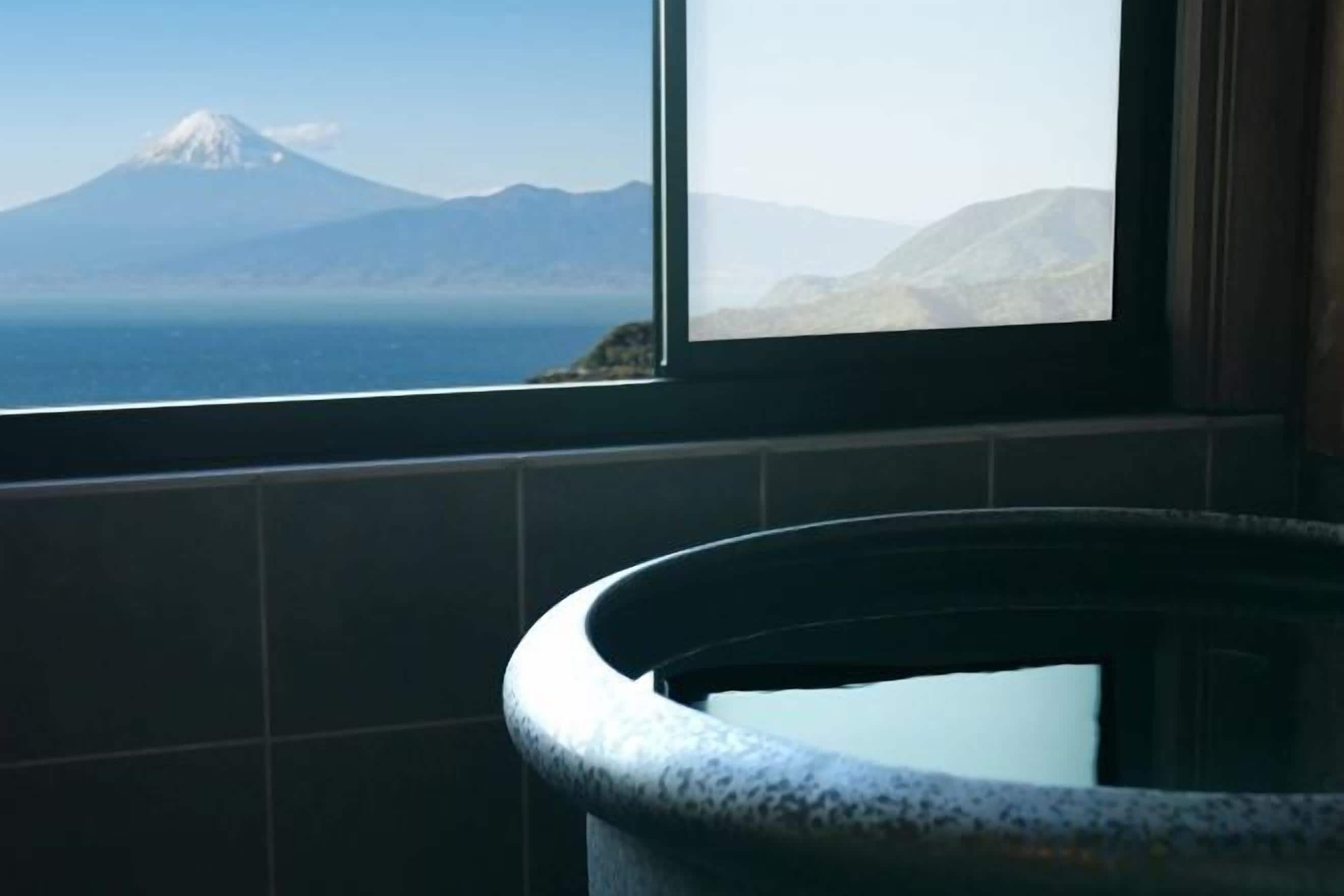 A bathroom with a view of a mountain and a body of water through a window.
