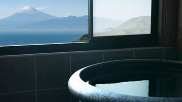 A bathroom with a view of a mountain and a body of water through a window.
