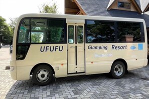 A shuttle bus parked outside a building with a sign that reads 'Glamping Resort.' - Nishi-izu Glamping Tenkuu-Terrace (Numazu)