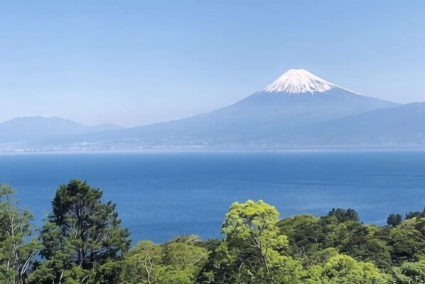 A view of a mountain with a snow-capped peak, a body of water in the foreground, and a clear sky. - Nishi-izu Glamping Tenkuu-Terrace (Numazu)