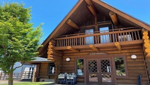 A log cabin with a balcony, a sign reading "KUMO TO KAZETO", and a view of the surrounding area. - Nishi-izu Glamping Tenkuu-Terrace (Numazu)