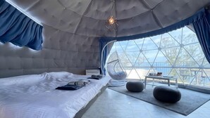 A modern room with a large bed, a hanging chair, and a view through a large window. - Nishi-izu Glamping Tenkuu-Terrace (Numazu)