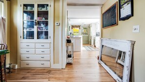 Une cuisine avec un plancher en bois, un meuble blanc aux portes en verre et un calendrier fixé au mur.