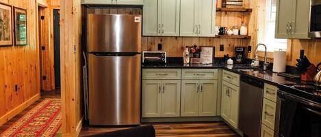 A modern kitchen with wooden walls, a stainless steel refrigerator, a microwave, and a sink.