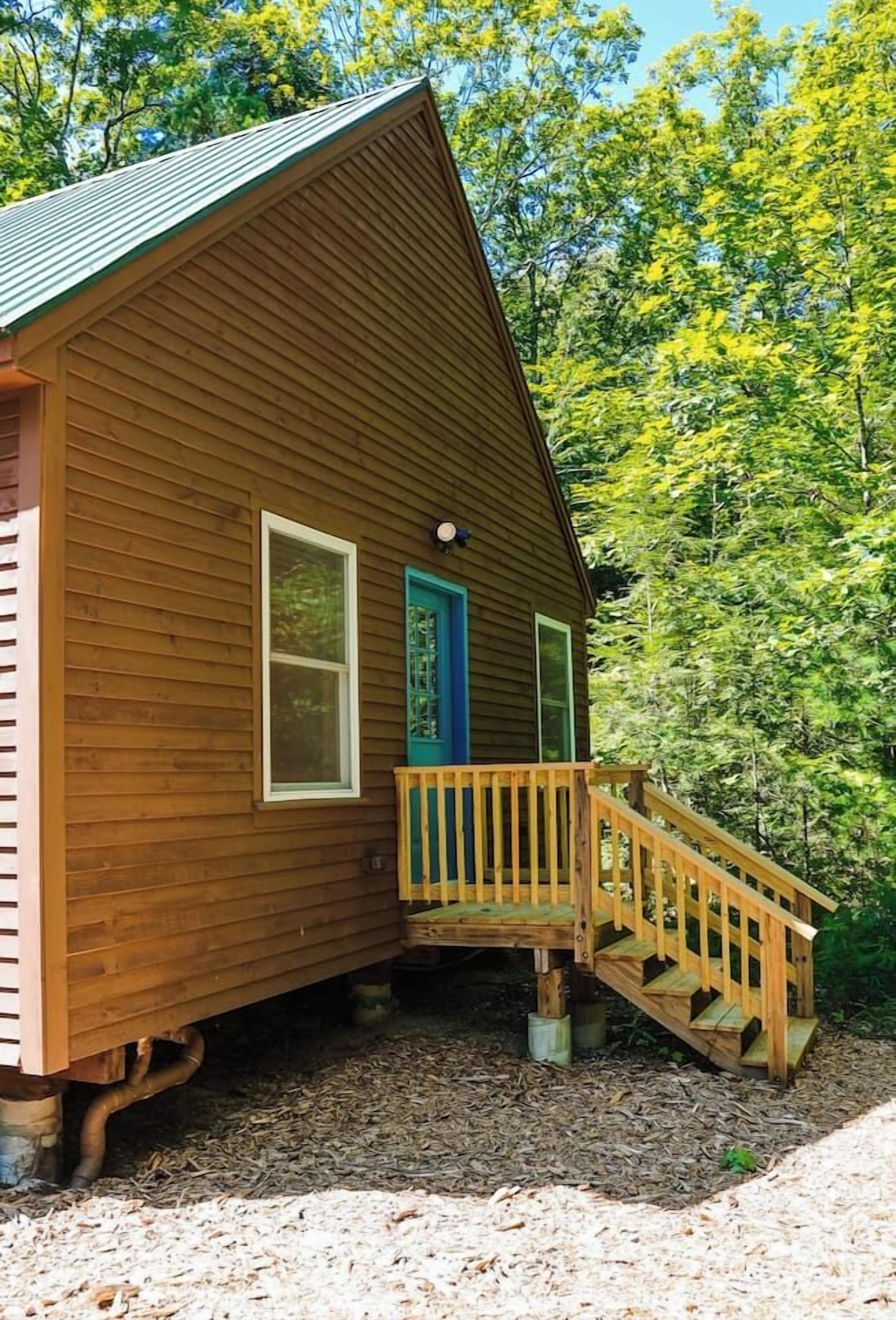 A wooden cabin with a wooden deck and a blue door.