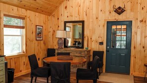Ein Holzblockhaus-Interieur mit Essbereich, einer Küche und einer Tür mit Fenster.